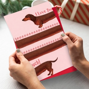 Detail of dachshund love greeting card with red envelope and festive holiday decor