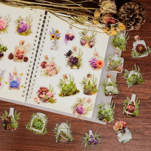 Detailed view of floral PET stickers in glass bottles on a vintage wooden desk