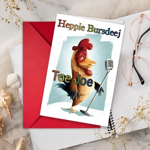 Funny cartoon rooster birthday greeting card with red envelope on marble table