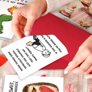 Detailed shot showing hands putting a humorous card with funny quote into a red envelope