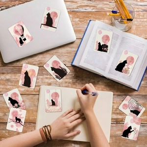 Detail of pink watercolor cat silhouette cards and stickers on a wooden desk