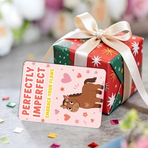 Détail d'une carte poney rose avec texte 'Perfectly Imperfect' sur une boîte cadeau