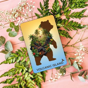 Flat lay of artistic volcanic island bear silhouette card with tropical scenery and ferns