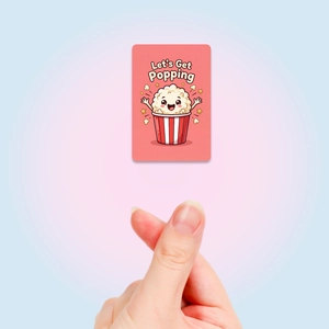 Nahaufnahme der Popcorn-Karte mit „Let's Get Popping“ Text und Herz-Finger-Geste