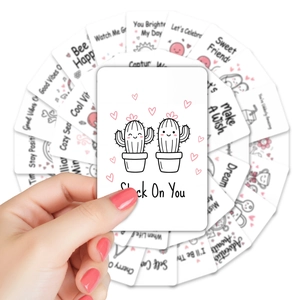 Close-up of hand holding cute lunchbox notes with motivational English quotes and drawings
