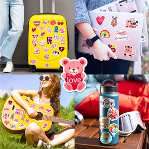 Detail of pink Valentine heart stickers applied on suitcase and laptop surfaces