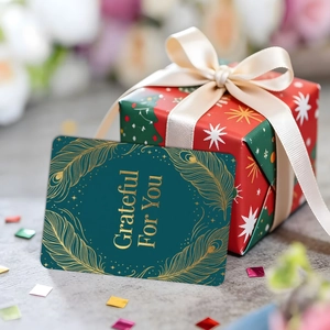 Biglietto verde scuro con trama dorata e confezione regalo rossa con fiocco elegante
