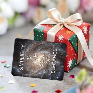 Cosmic galaxy art card with elegance quote leaning on a red festive gift box decoration