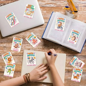 Detail showing various animal-themed birthday cards scattered on a wooden desk setup