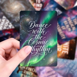 Detail of hand holding galaxy oracle card with 'Dance with the Cosmic Rhythm' text