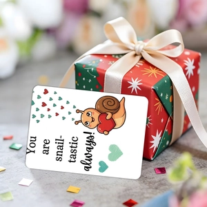 Detail of snail-tastic card leaning on a red gift box with golden festive ribbon