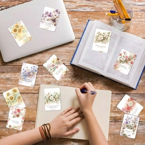 Dettaglio di carte floreali con citazioni e fiori ad acquerello su scrivania in legno