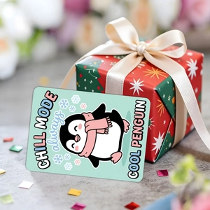 Nahaufnahme einer mintgrünen Pinguin-Karte an einer roten Geschenkbox mit Schleife
