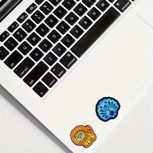 Neon peacock and lion stickers on laptop surface showing glowing waterproof design