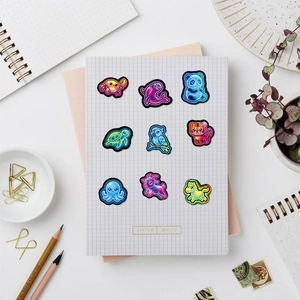 Close-up of cute neon animal stickers including crab and panda on a grid notebook