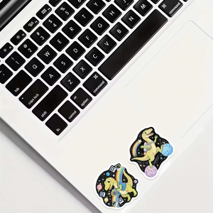 Detail of waterproof cartoon dinosaur astronaut and photographer stickers on a laptop