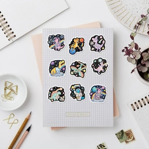 Detail of waterproof cartoon space dinosaur stickers on a white grid notebook cover