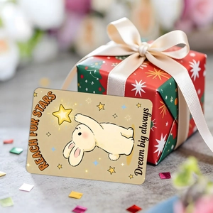 Close-up of a cute rabbit card with Reach for Stars text next to a red gift box