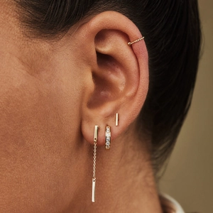 Gros plan détaillé d'un ensemble de 4 boucles d'oreilles dorées sur l'oreille d'une femme