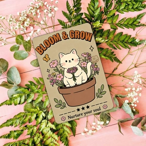 Detail of cartoon cat illustration card with Bloom & Grow quote on pink wood background