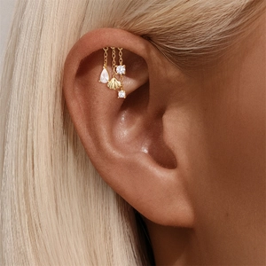 Detalle de piercing de plata s925 con conchas doradas y borlas de circón brillante