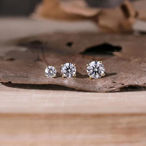 Macro view of three different sized moissanite screw back earrings on natural leaf