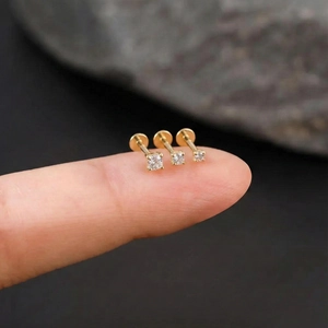 Macro view of gold S925 silver labret studs with round and square moissanite on a fingertip