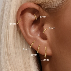 Detail shot of gold beaded piercing rings in 6mm, 8mm, and 10mm sizes on ear