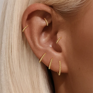 Close-up of gold beaded silver cartilage earrings set worn on different ear positions