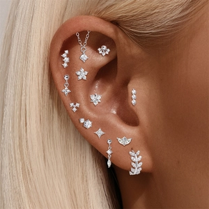 Macro shot of S925 silver cartilage studs with flower and marquise chain motifs