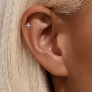 Macro shot of s925 silver four-pointed star cartilage earring with sparkling moissanite