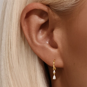 Detail of gold teardrop crystal drop earrings worn by a model in a high-end close-up