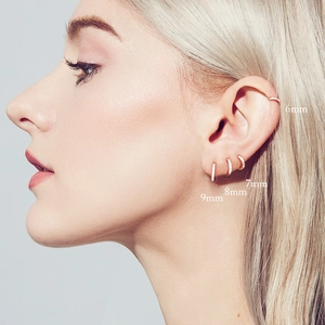 Detailed view of 18k rose gold huggie earrings in 6mm, 7mm, 8mm and 9mm sizes on ear