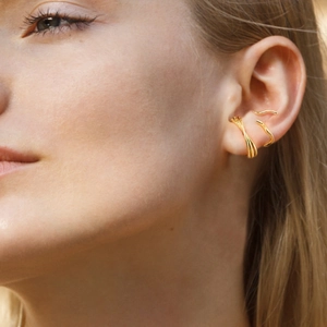 Vista detallada de tres ear cuffs dorados con texturas geométricas minimalistas