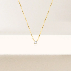 Detalle de collar minimalista de plata S925 dorada con colgante de circonita de cuatro garras