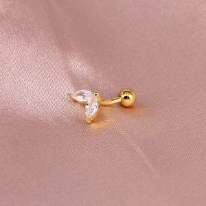 Macro shot of gold-plated marquise zircon leaf stud earring on pink silk background