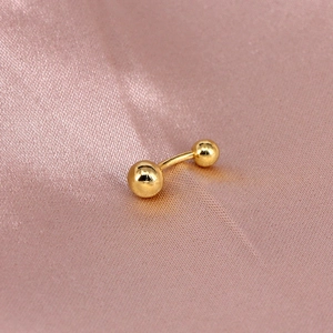 Close-up of golden S925 sterling silver curved barbell piercing with polished ball ends