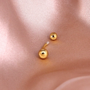 Macro shot of gold navel piercing showing internal screw thread and polished finish