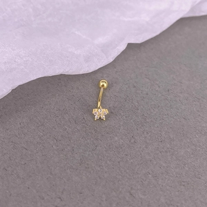 Macro shot of a gold belly ring featuring a sparkling five-petal flower with clear zircons