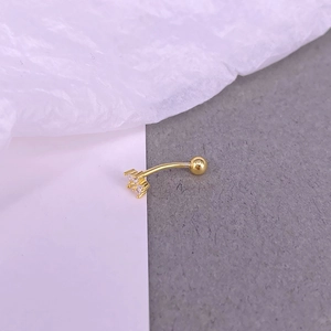 Gold curved barbell piercing with floral zircon cluster on a textured background