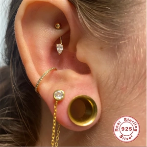 Macro shot of 925 silver ear piercings with drop zirconia and paved crystal details