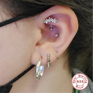 Detailed view of S925 sterling silver floral and hoop piercing studs on the ear