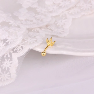 Detailed shot of golden crown belly button ring with zircon inlay on white lace