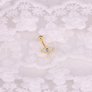 Macro detail of golden Evil Eye belly ring with blue gem on white lace background