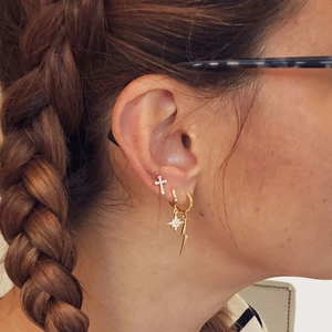 Details von goldenem Piercingschmuck mit Kreuz, Stern und Blitz Zirkonia-Ohrsteckern