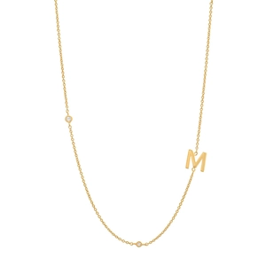 Gros plan du pendentif lettre M dorée avec deux pierres claires serties brillantes