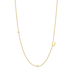 Détail macro du collier doré avec pendentif lettre U et trois pierres de zircone fines