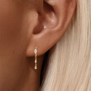 Close-up of a gold S925 silver hoop earring with marquise and teardrop crystal drops