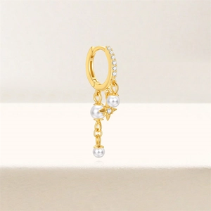 Detail of gold hoop earring with dangling pearls and central sparkling star charm