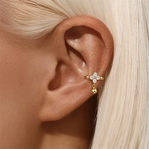 Macro shot of gold ear cuff with flower zircons and polished bead on model ear